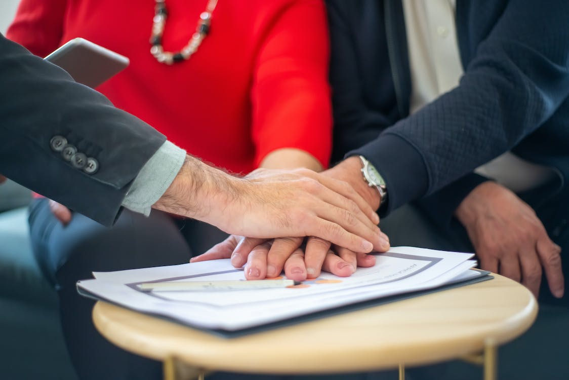 A group of people placingtheir hands on a document